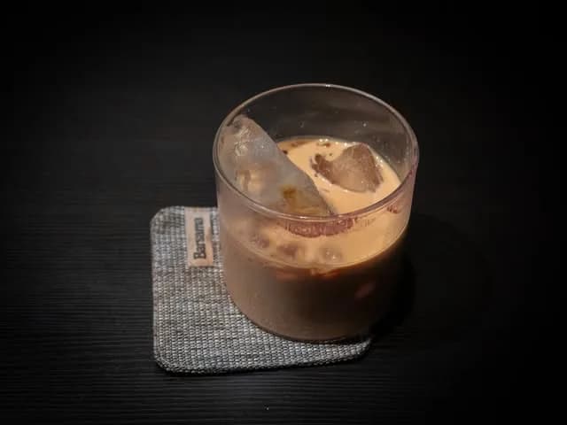 An iced milk coffee on a grey coaster