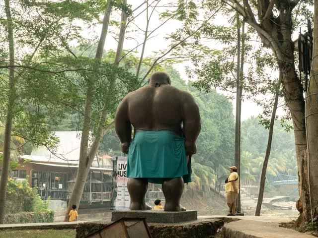 A statue of a broad figure in a park